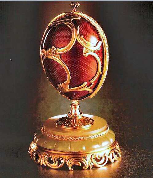 It consists of a case made of white maple covered in leather with steel hinges and clasps containing a smaller egg (the official "Fabergé" egg) decorated in red enamel and gold scroll work placed upright on a small stand of carved bowenite which then opens vertically to reveal