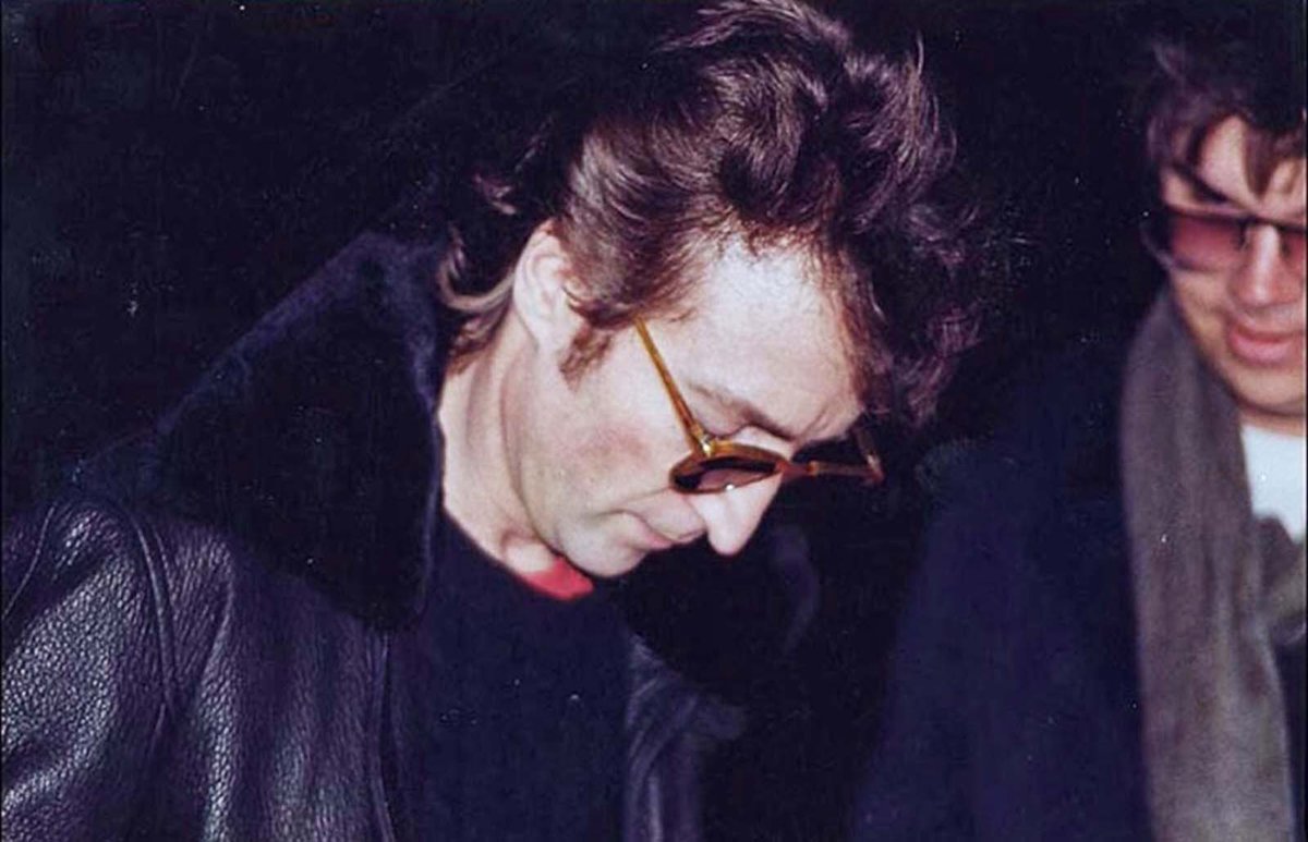 JOHN LENNON SIGNING AN AUTOGRAPH FOR HIS KILLER, MARK CHAPMAN.