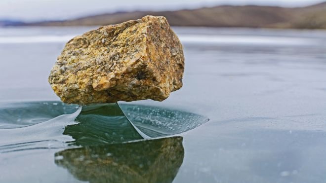 Le vent pousse parfois des pierres sur le lac gelé Baïkal, en Russie, et une fois qu'elles sont chauffées par le Soleil, elles font fondre partiellement la glace sous elles créant un effet visuel très élégant et insolite !