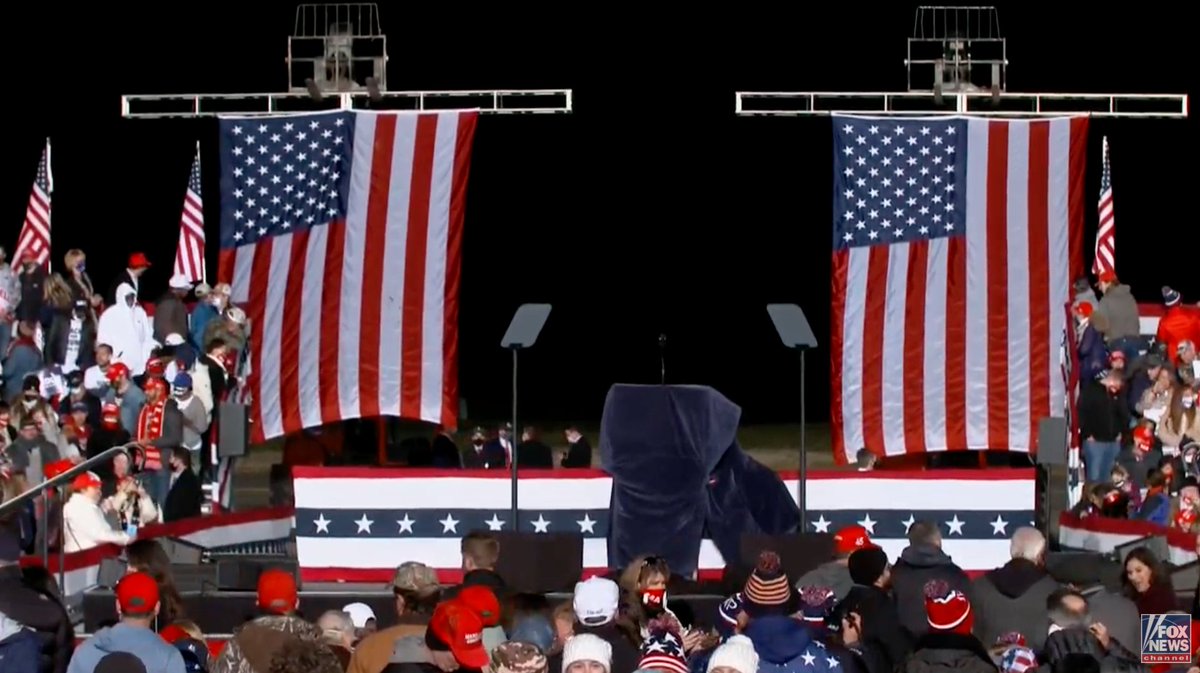 21/ The set-up of the stage in Dalton is a *great* metaphor: two giant American flags with a large space between them—a space set against the black of night behind it so that it looks like a bottomless Abyss. When Trump arrives, he will enter through that Abyss. To wild applause.