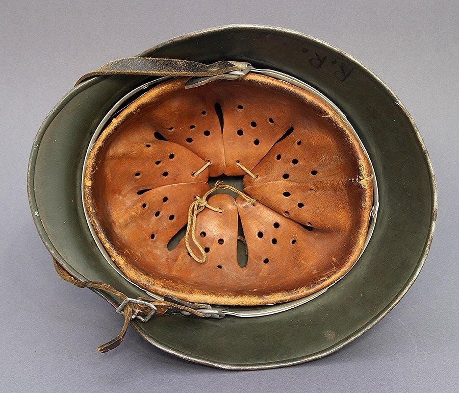 Here we see the M31 aluminium liner band, secured by the 3 rivet pins, 8 finger perforated drawstring leather liner (for ventilation) & leather chinstrap attached & secured by buckles. Note the rolled beaded rim folded beneath the Stahlhelm. 6)