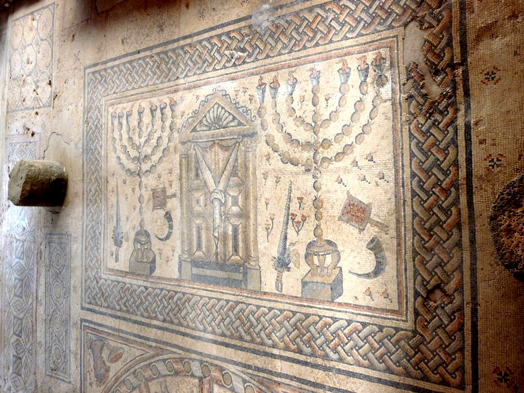 You can see there that Sol is in the middle of a zodiac wheel, a common motif in the Roman empire. And above, there are two menorahs and a Torah shrine. The zodiac signs are labeled in Hebrew, but Greek is also present.