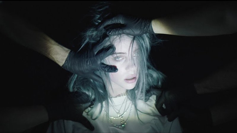 Les mains emmènent avec force Billie d'un endroit à un autre. Elle a l'air complètement ailleurs pendant que les mains simulent des abus et des étranglements.