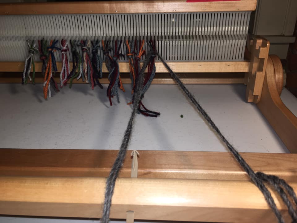 24/ Now you have to connect these knots to the front roller of the loom. So you thread a long piece of yarn through the top and bottom threads allowing the knot to old it on the inside.