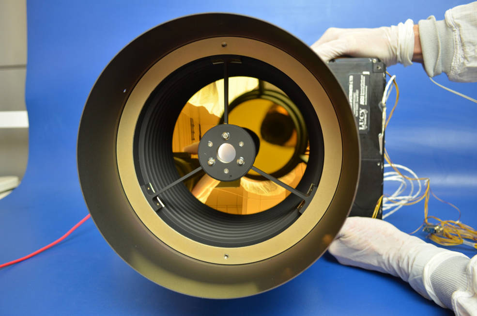 gloved technician holding what looks like a large camera lens