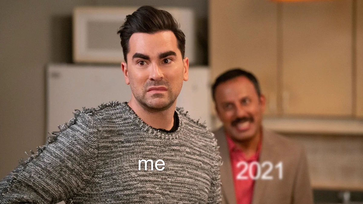 Dan Levy and Rizwan Manji from Schitt’s Creek as David and Ray. David (“me”) looks worried, with Ray (“2021”) slightly out of focus in the background smiling at him.