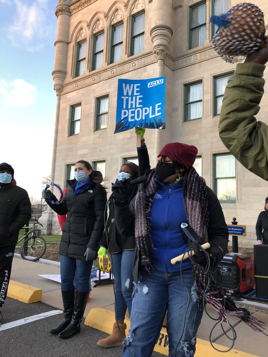 People at the north side of the state capital. One person holding the mic. One person behind holding a sign that reads “we the people”. Top right hand corner of the photo seems to be a maraca in action.