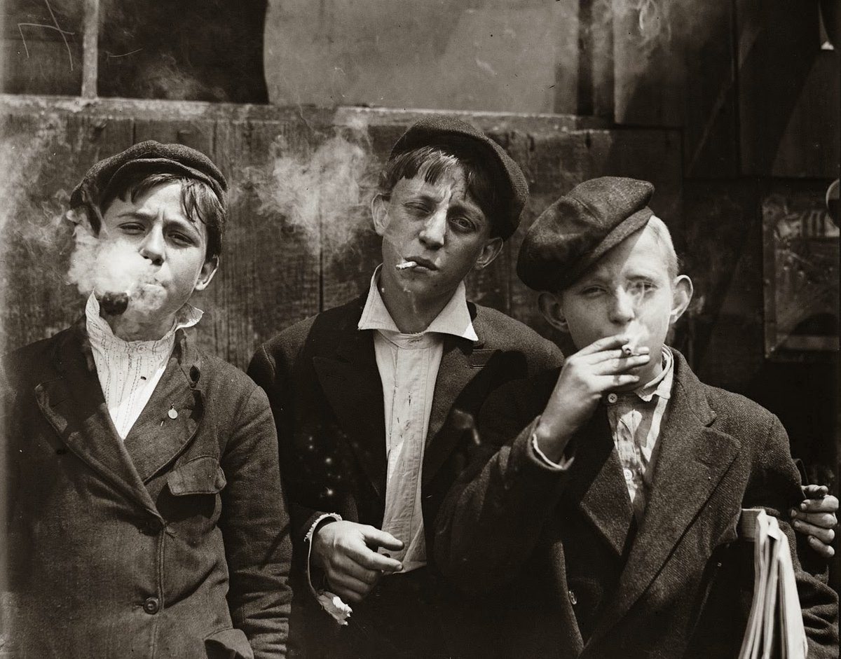 11:00 A. M . Monday, May 9th, 1910. Newsies at Skeeter's Branch, Jefferson near Franklin. They were all smoking. Location: St. Louis, Missouri.Photo by Lewis Hine.