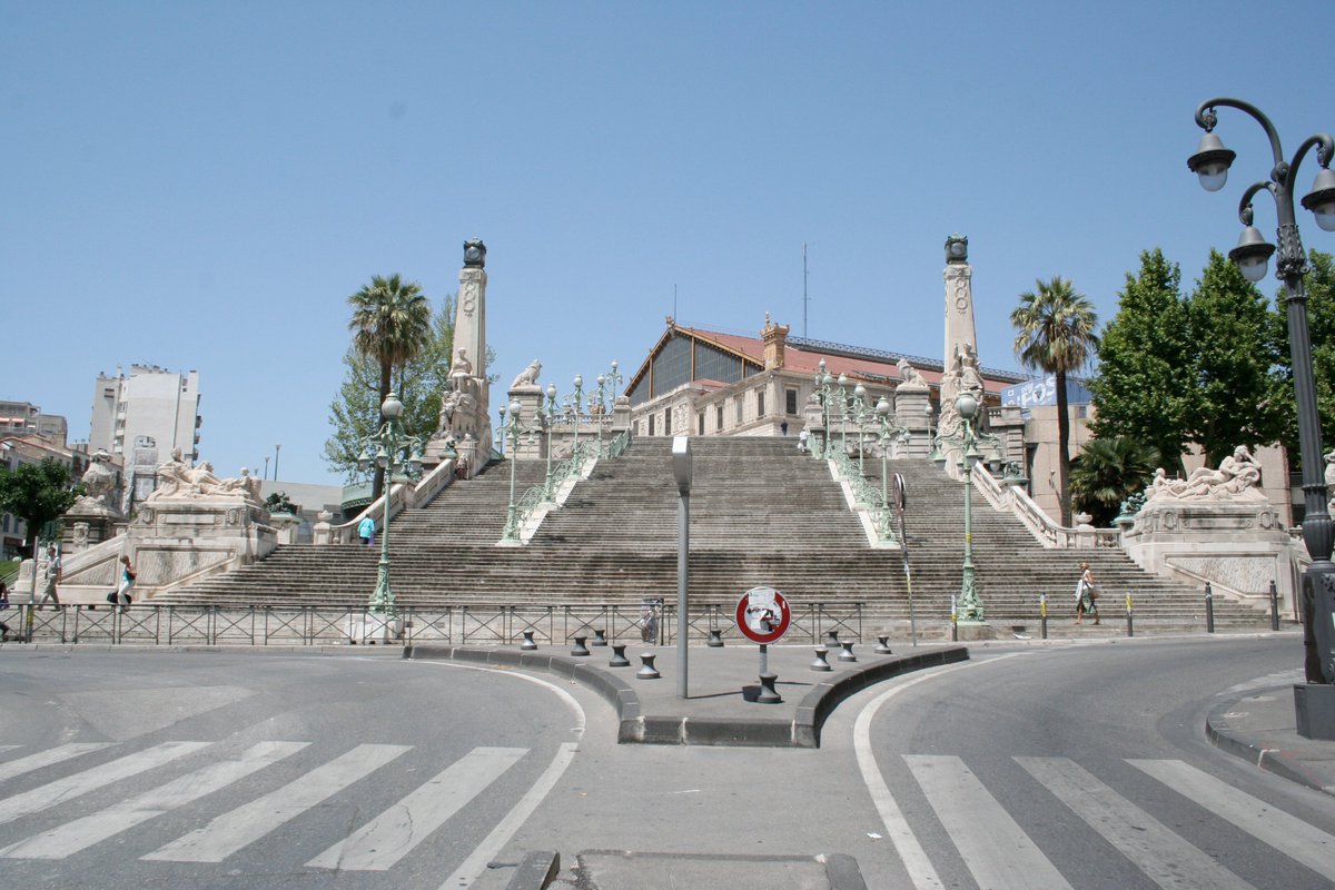 From here, if we walk up the Boulevard d'Athènes, we arrive at one of the city's most famous landmarks, the monumental staircase of the Gare Saint-Charles (1927). Flanked by statues of the colonies of Africa and Asia, it displays Marseille's status as the gateway to the empire