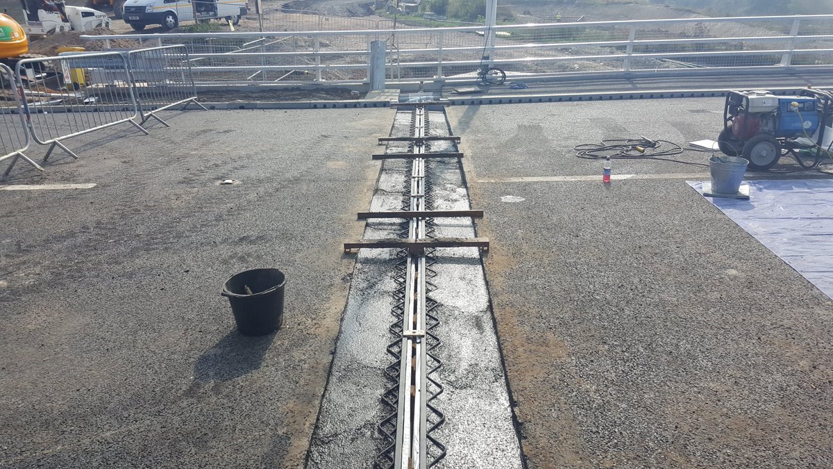 Rail joint; a flexible rubber/plastic strip spanning the gap, gripped by steel rails set into the road. Different cross-sections exist depending on manufacturer but the principle is the same. Used on non-integral bridges for approx ± 75mm movement.