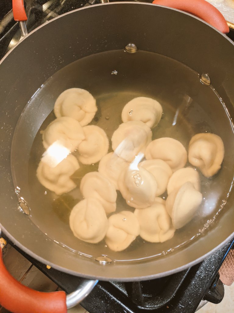 When all your pelmeni are ready put them into the boiling water. I'm doing it in batches. They sink when you put them in, as shown here. In about 7 minutes they'll all rise and should be ready.