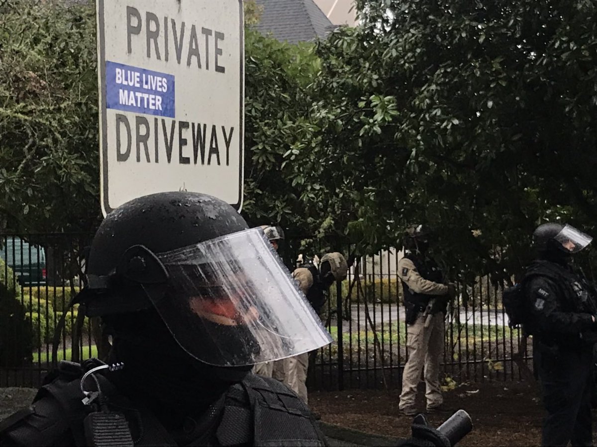 Man hold signs reading “Kate Brown dictator clown”