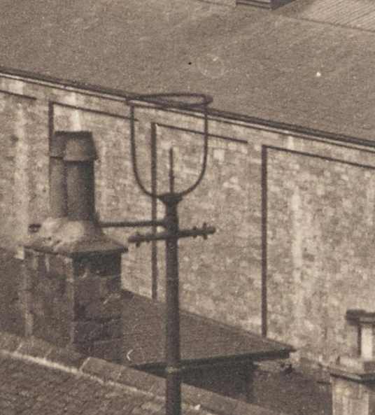 The gas lamps of North Bridge, the first such lamps in Edinburgh, introduced 1819. The cross-piece is for the leerie's (lamp lighter's) ladder. The gas spigot comes straight up through the standard. The first lamp has its glass bowl and chimney, the other is missing.