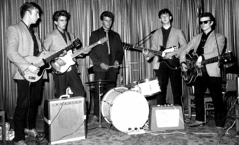 In 1960, John’s band changes their name to “the Silver Beetles” and begin to perform in clubs in the red light district of Hamburg, Germany.George is deported for being under-age while Paul & drummer Pete Best are deported for nailing a condom to a wall and setting it on fire.