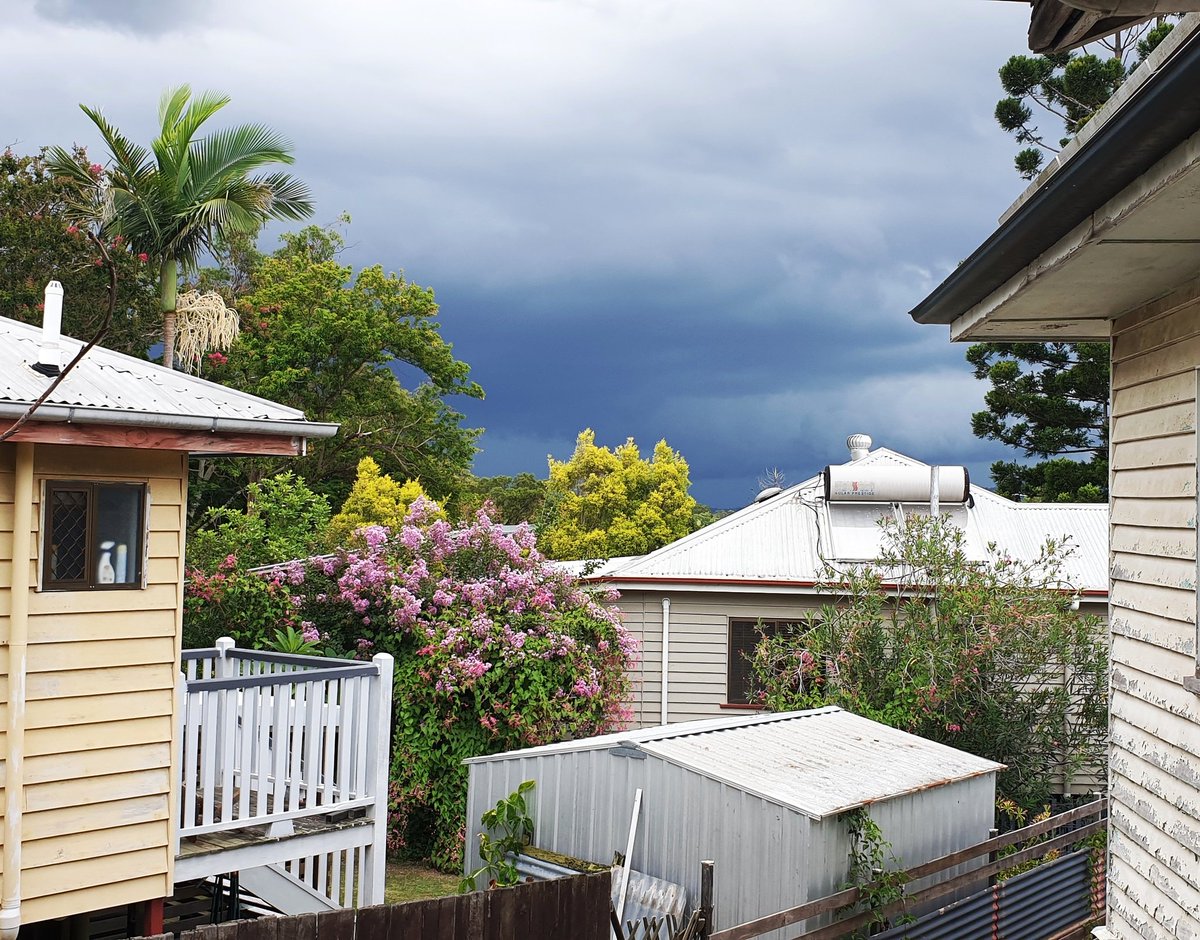 Between two old wooden houses, above rooftops, very dark grey sky in the distance.