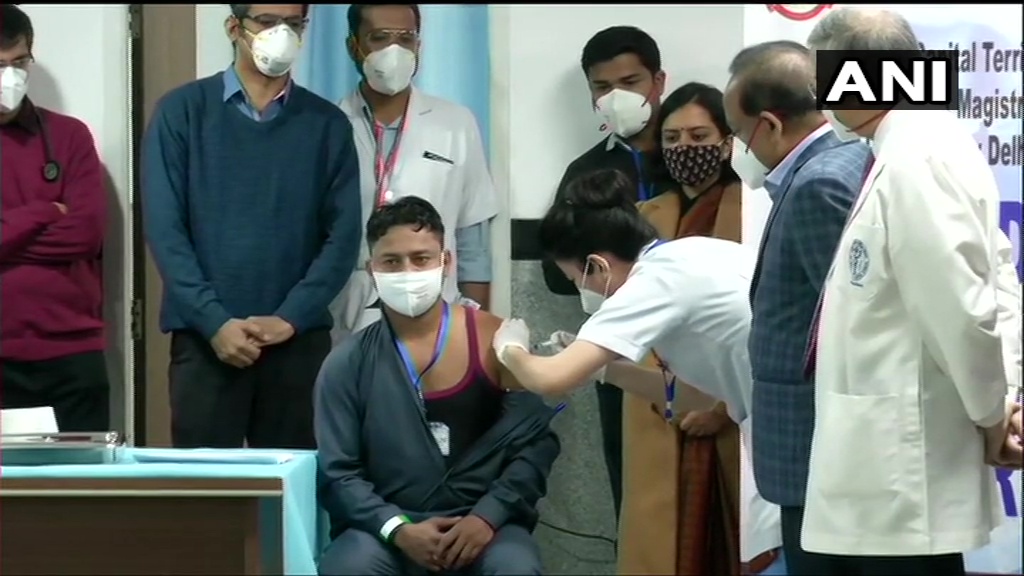 Delhi: A sanitation worker becomes the first person to receive COVID-19 vaccine jab at AIIMS. Union Health Minister Harsh Vardhan is also present.  (ANI) 
Track #Covid19 latest updates here bit.ly/3qCHv5F