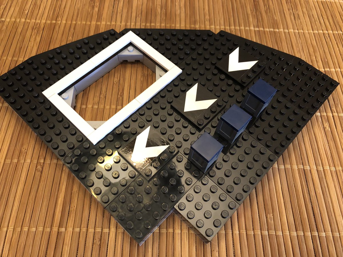 This section has a hole in the all black floor with light grey trim, a white border, and directional markings on top.  #LEGO  