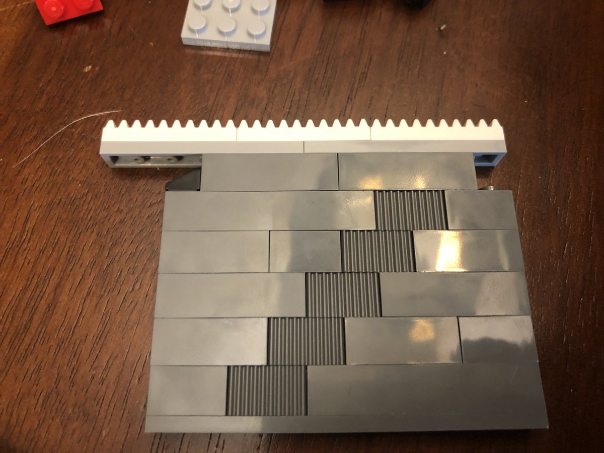 As we go, we find there’s a one block gap on the left side, and then we build a door that fits in the gap. There’s a little gear track on top, so it’s gonna have a mechanism later.  #LEGO  