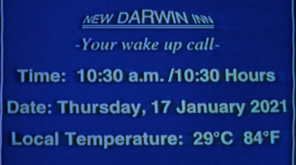 Text on a screen. It reads "New Darwin Inn: Your wake up call. Time: 10:30 a.m./10:30 Hours. Date: Thursday, 17 January 2021. Local temperature: 29 degrees C, 84 degrees F."
