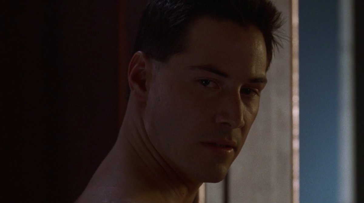 A handsome, light-skinned man with dark hair turns to look over his shoulder