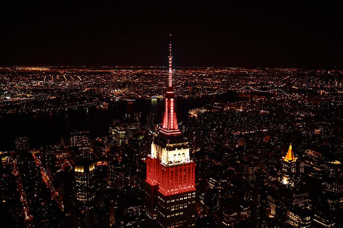 EmpireStateBldg's tweet photo. When pig(skins) fly… 🏈 
  
Our tower shines in crimson &amp; white tonight, congratulating @AlabamaFTBL’s DeVonta Smith for taking home the @HeismanTrophy! #ESBright #RollTide https://t.co/zFXJpBTfa4