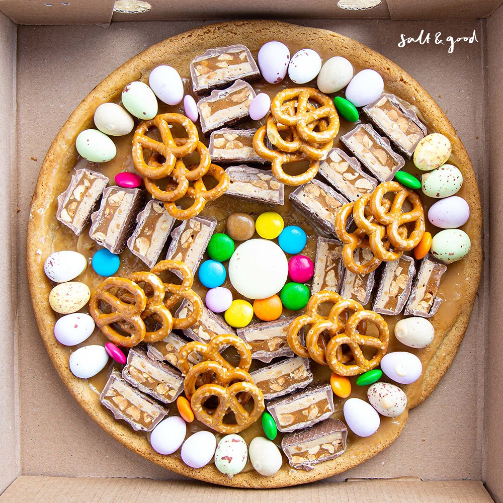 SaltandGood's tweet photo. Kick-off your mid-week blues with our Naughty but Nice. Our nine-inch cookie dough base, covered in salted caramel sauce, topped with snickers, smarties, mini chocolate eggs, and pretzels is an absolute treat for all. Order via https://t.co/IR4nXfnaaL for collection or delivery. https://t.co/hs4SXLpMJN