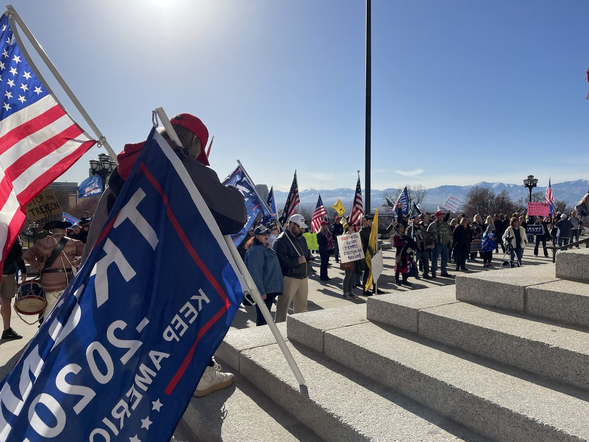 A speaker has a small megaphone and is speaking to a crowd from the steps. He reiterates unproven claims that the election was stolen and says “we need to stand up and make sure our legislators are in full awareness that this is a nation of laws.”