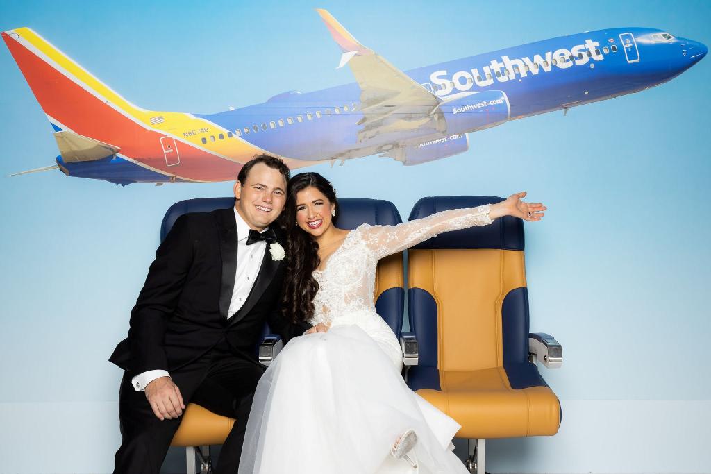 The wedding was one year later, complete with a Southwest exit row photo booth, Southwest snacks in the guest boxes, and more. BUT WAIT- it gets cuter. (5/7)