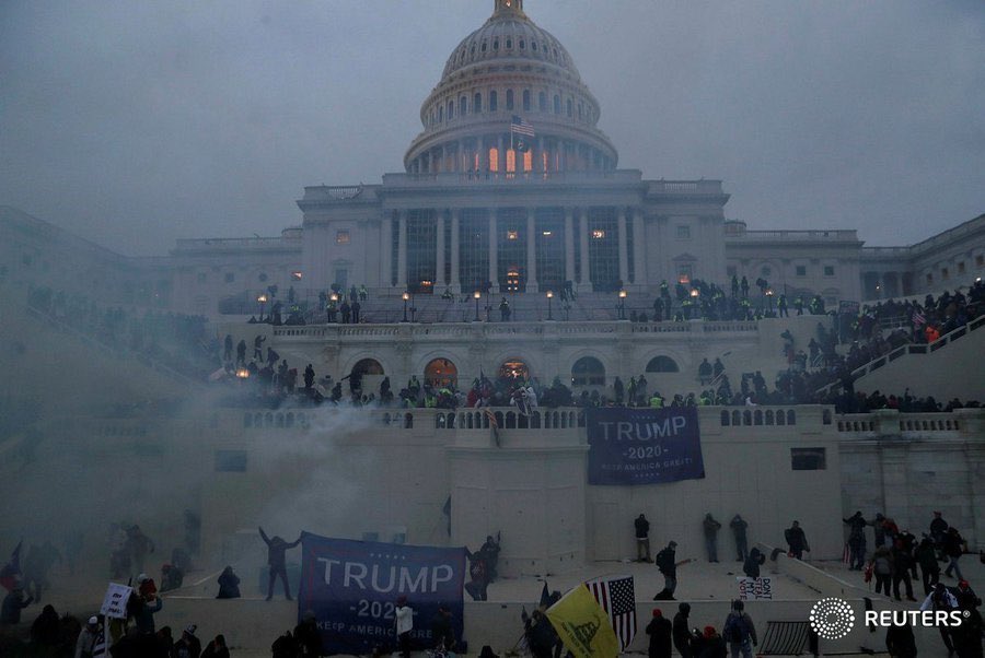 Φωτογραφία του Καπιτωλίου με δακρυγόνο (ή απλό) καπνό, πολλά τεράστια πανό "Trump 2020" και γενικά μεγάλο αριθμό ανθρώπων που στέκονται σε όλη τη σκάλα.