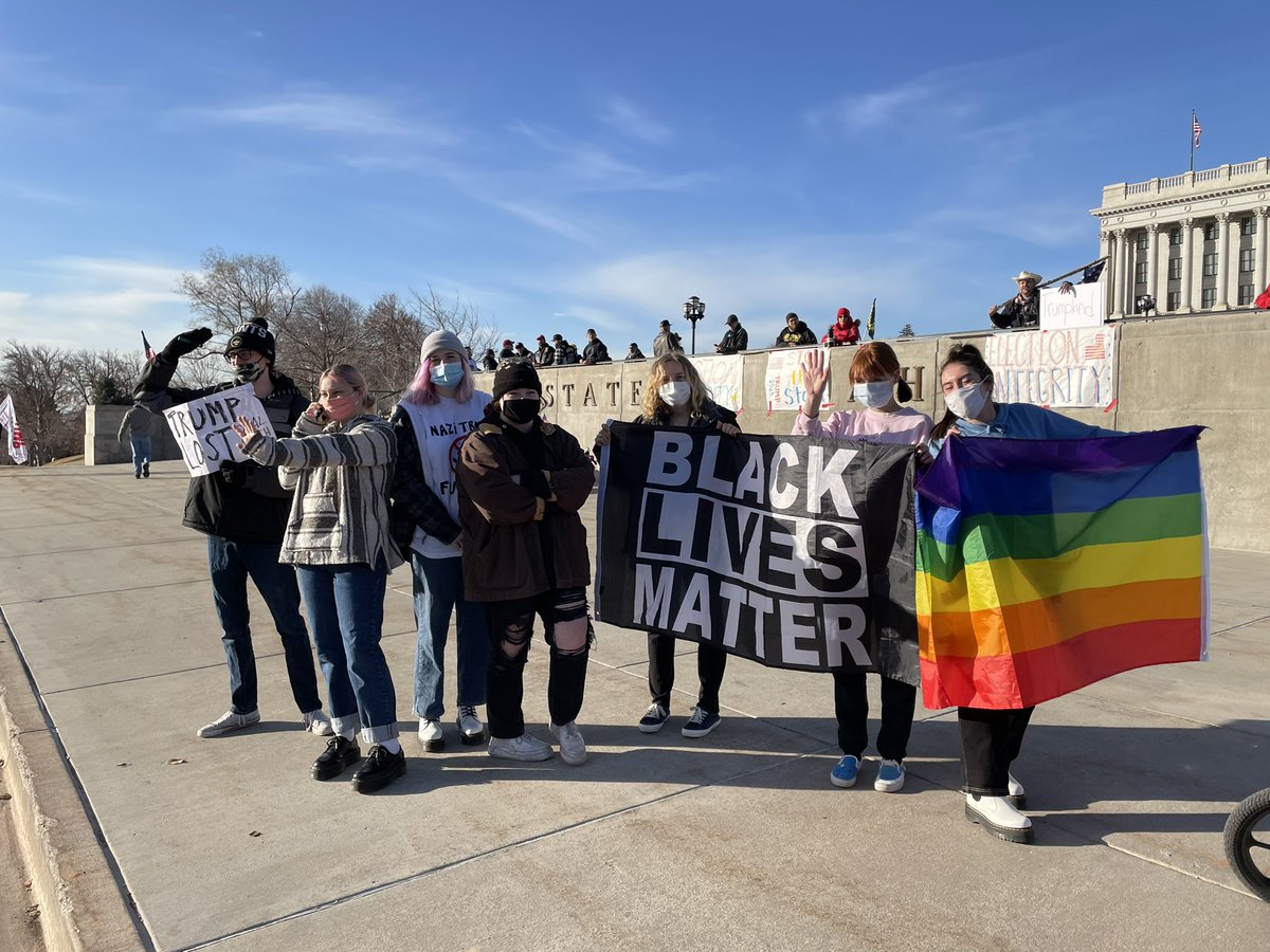 A small group of counter protestors hold a Black Lives Matter sign at the entrance to the Capitol. A guy with an American flag is yelling back, “All lives matter!”
