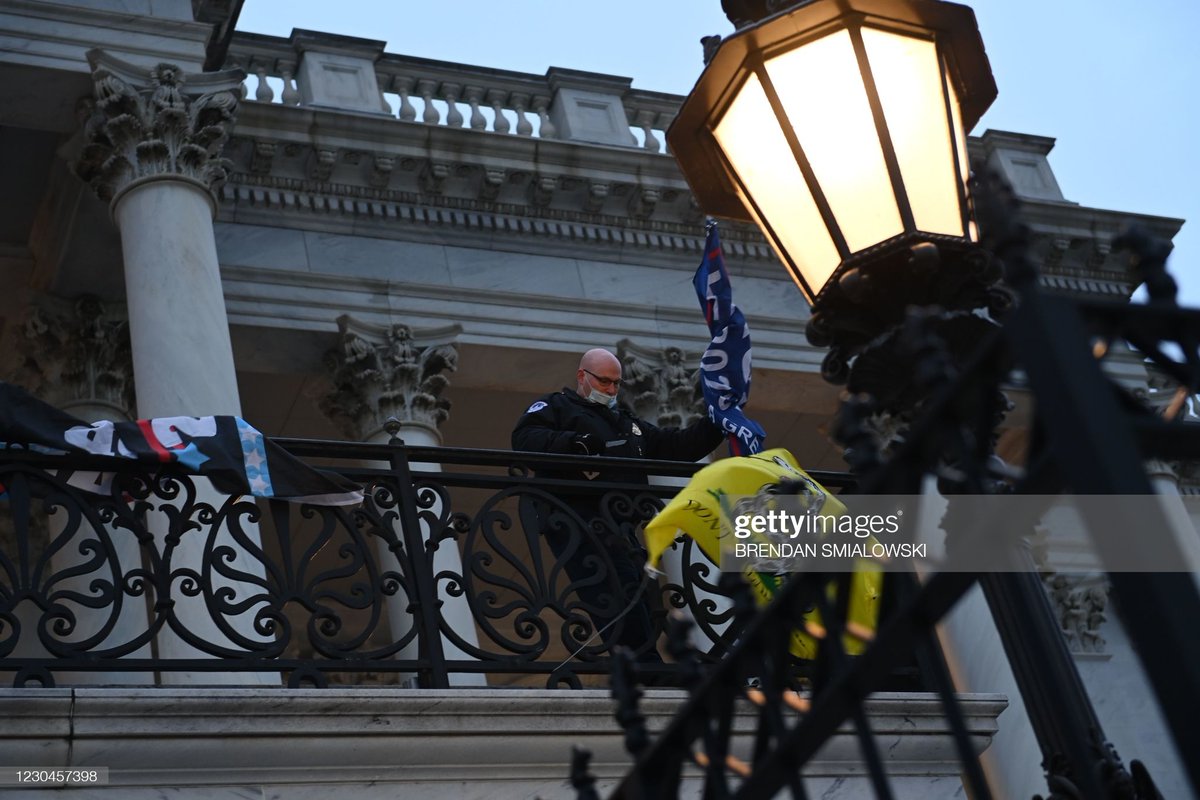 A police officer takes down a flag left hanging by protestors outside of the US Capitol in Washington DC on January 6, 2021.