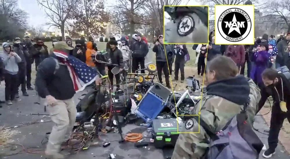 13) outside destroying press cameras and assaulting journalists, was National Anarchist Movement (N-AM), as much ‘anarchist’ as Nazis were national ‘socialists’, but a group whose goal is racial segregation and purity.