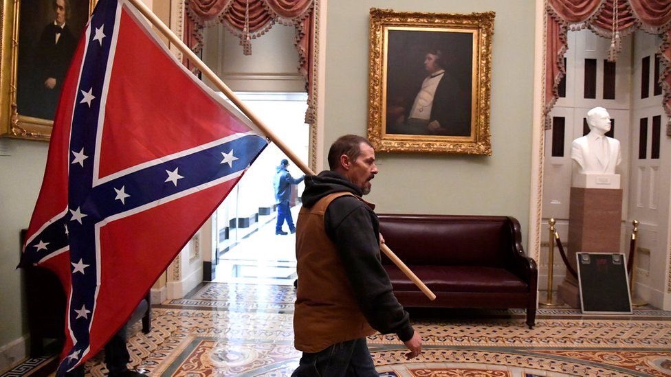 Photo from U.S. Capitol breach on January 6, 2021. Photo of white man carrying Confederate flag.