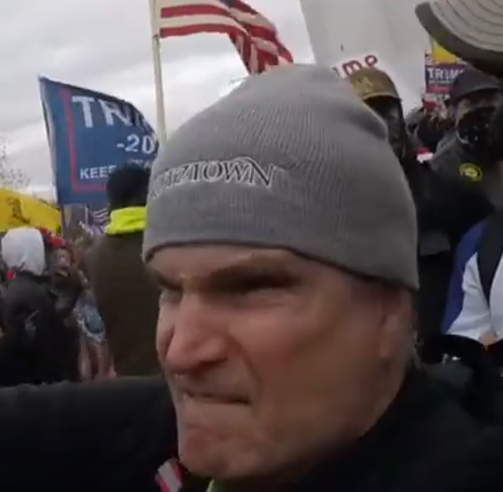 JakeGodin's tweet image. Images of the guy who was being super aggressive toward the journalist (there's something written on his hat "---ztown"?) and the one who assisted in pushing him over the stone railing (wearing camo with a backpack).