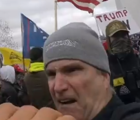 JakeGodin's tweet image. Images of the guy who was being super aggressive toward the journalist (there's something written on his hat "---ztown"?) and the one who assisted in pushing him over the stone railing (wearing camo with a backpack).