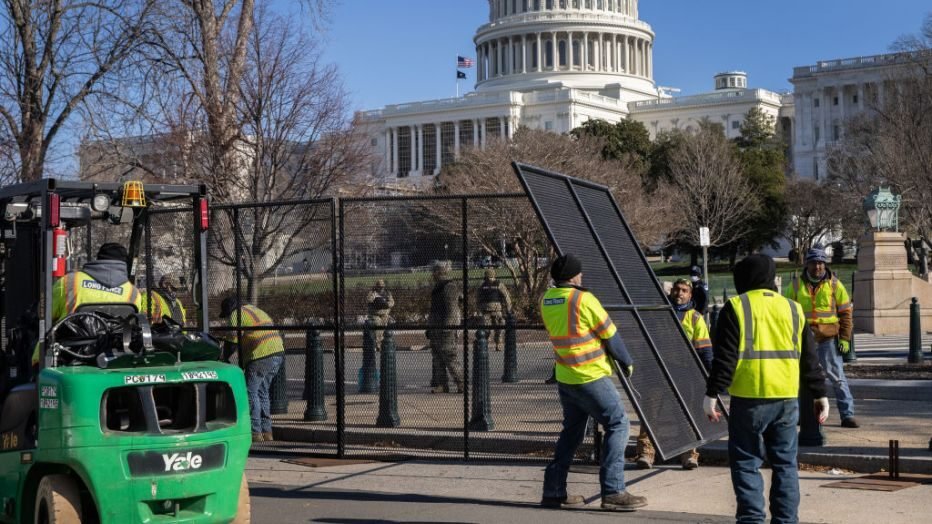 Workers setting up the modular fencing around the Capitol grounds. They come in pieces roughly 8 feet by 8 feet. One of them seems to be being hauled by one worker by himself. Unwieldy due to the size but it looks possible to carry a piece by yourself.