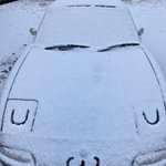 車のボンネットに積もった雪で作ったかわいい顔!