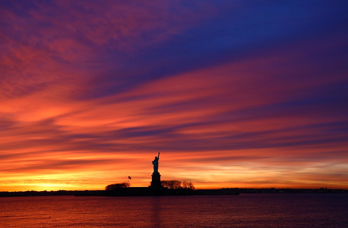 GaryHershorn's tweet photo. I went out to see the moon rising next to the Statue of Liberty this morning  but instead was treated to an explosion of color as the sun rose in New York City #newyork #newyorkcity #nyc @statueellisnps @agreatbigcity #sunrise https://t.co/jqt0ZvWaqk