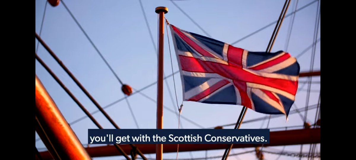A Union flag, on a flagpole, outstretched in the wind. In the background, the cables and ropes of a sailing ship.

Subtitles: "you'll get with the Scottish Conservatives."