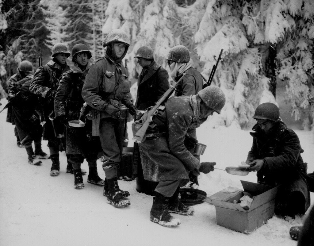 WW2Facts's tweet photo. #American soldiers from the 347th Infantry Regiment line up for chow during a lull in the fighting in Battle of the Bulge on January 13, 1945.

#History #WWII https://t.co/DxR7Y2vmoS