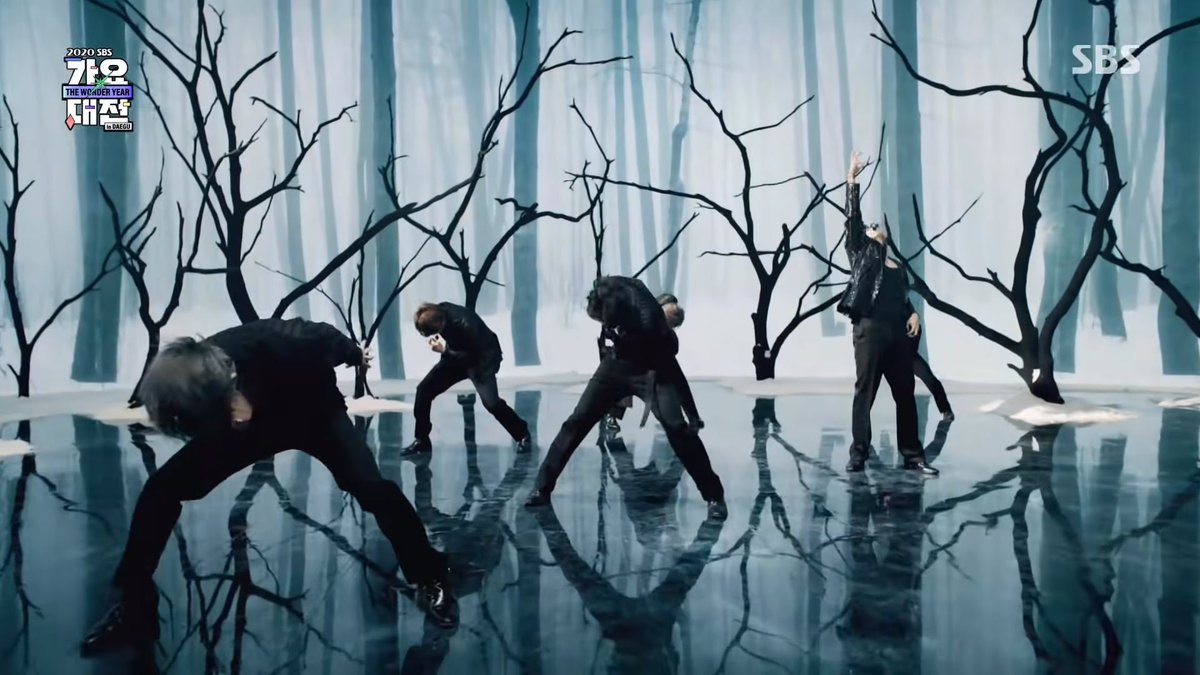 In latest Black Swan performance, the lake is frozen. It's winter time. There is snow around the lake. Not surprising for a Dec 25 performance with bells tinkling when the song starts.The trees are bare, but there is something weird. They are black... charred trees? @BTS_twt
