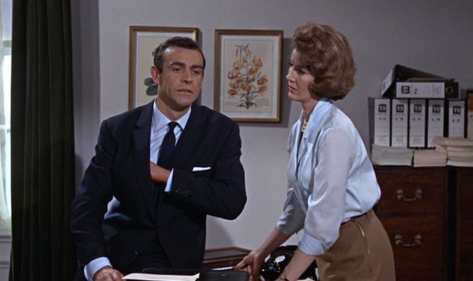Sean Connery and Lois Maxwell in an office wearing blue shirts