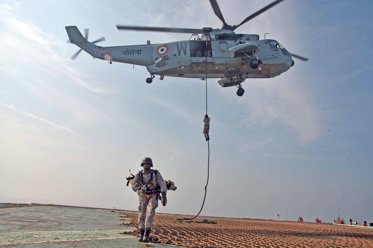 ANI's tweet photo. A Navy Special Forces commando slithered down the SeaKing multirole helicopter, with his dog on his back, during the Naval Sea Vigil exercise. https://t.co/exqglY0gz0