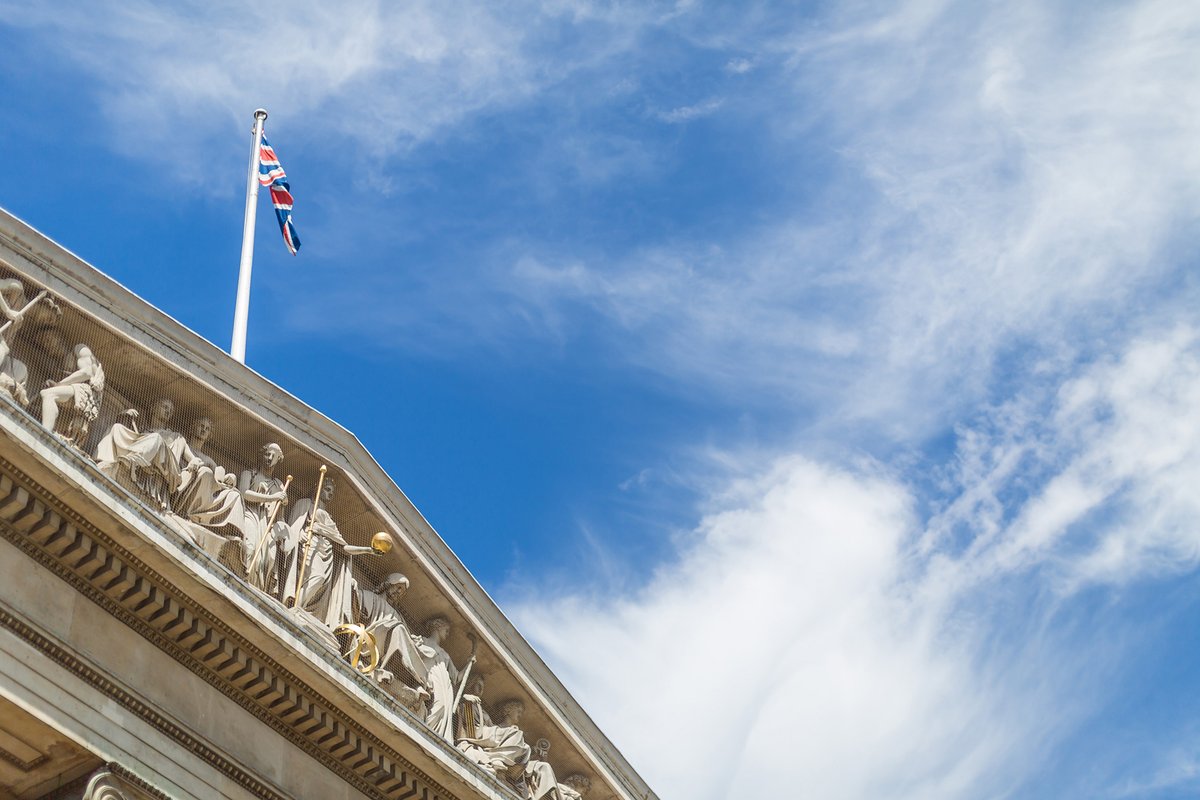 A photograph of the front of the Museum and the pediment, against a background of a cloudy blue sky. 