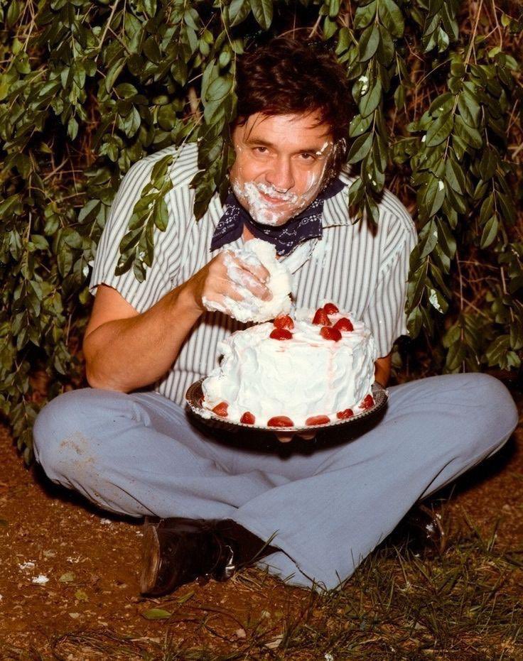 Johnny Cash eating a cake in a bush. The iconic picture was taken for his 1975 album Strawberry Cake.
