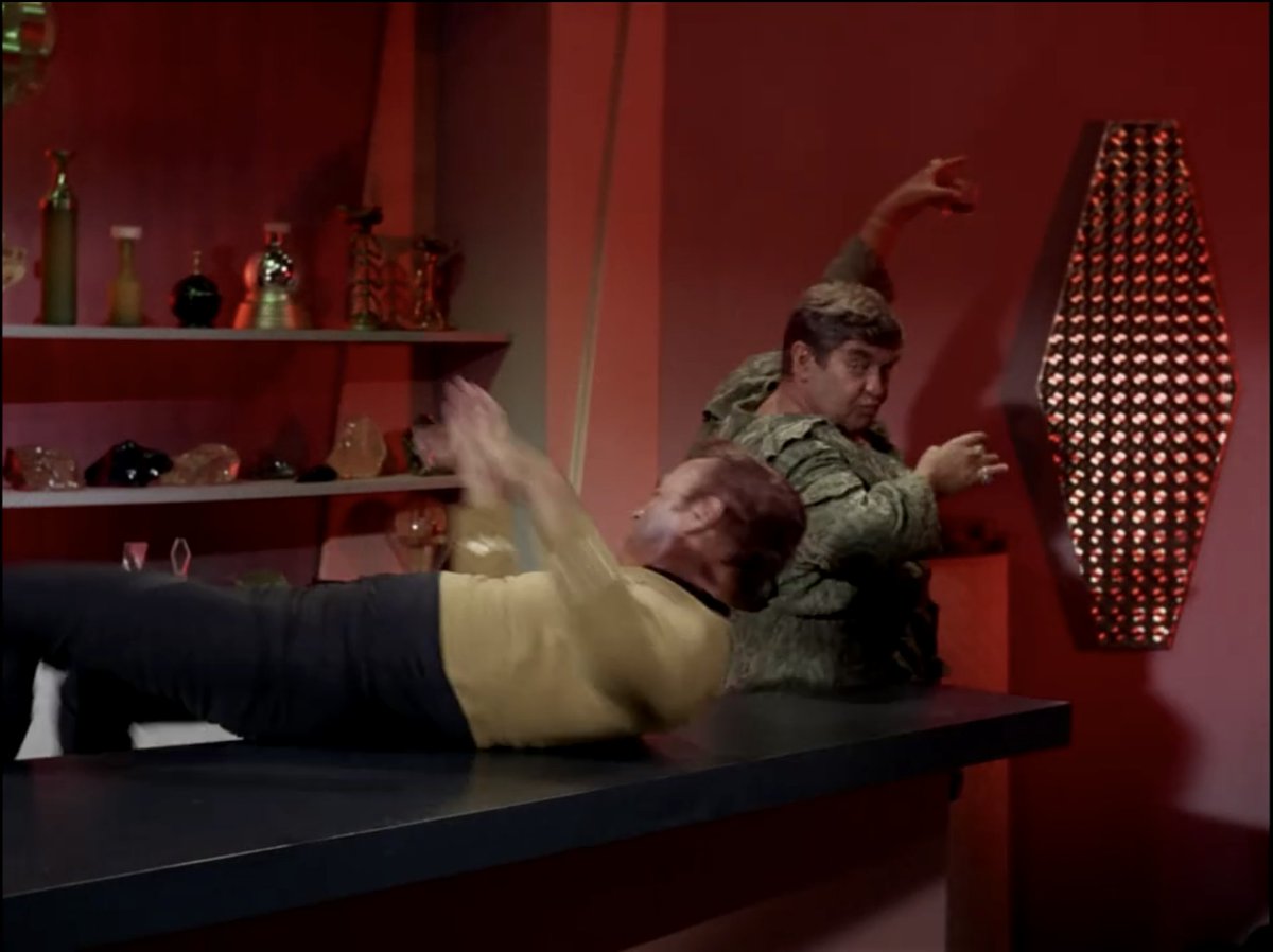 As he exits with her, he walks through the party with his drink raised high to protect it and take it with him. And because I've seen 'The Trouble with the Tribbles' (S2:E15) about 1000 times (although not lately)(4/9)