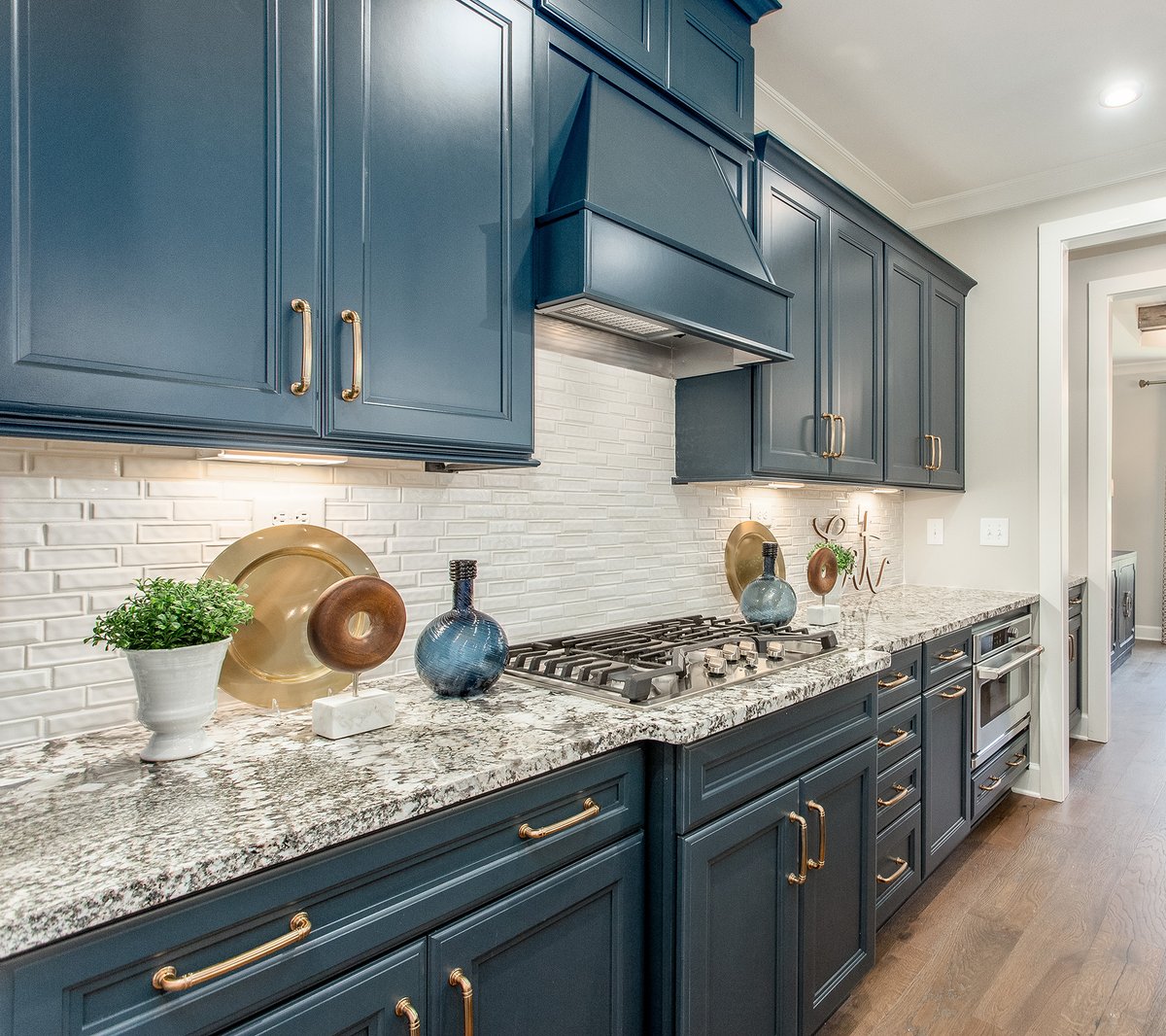 Yay or nay? What do you think of these blue painted cabinets with gold hardware accents? We are team YAY. LOVE the touch of drama & splash of color it adds! #modelhome #kitchendesign #paintedcabinets #maritimeblue #shawflooring #modelmerchandising #masterpiecedesigngroup