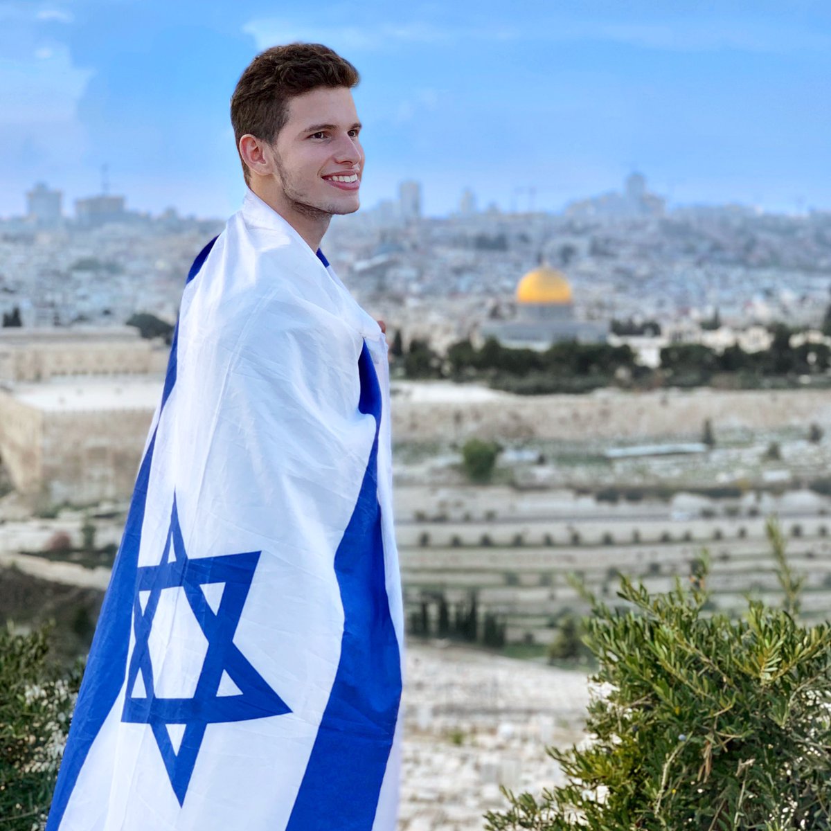 Noam_Chen's tweet photo. This is Rafael, who made #Aliyah to #Israel during the Covid pandemic. This was his first and emotional visit to the Mount of Olives in #Jerusalem, wearing the flag he came down the plane with. Check out my instagram for the full story behind this photo: https://t.co/JDmxv8b9K2 https://t.co/dkDQCLAjV5
