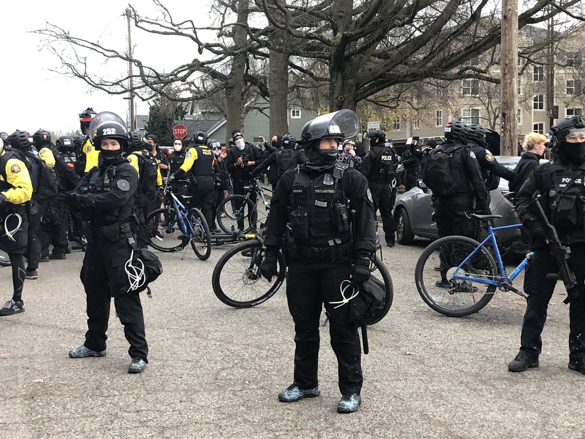 Two people arrested, handcuffed. Officers stand between them and the crowd.