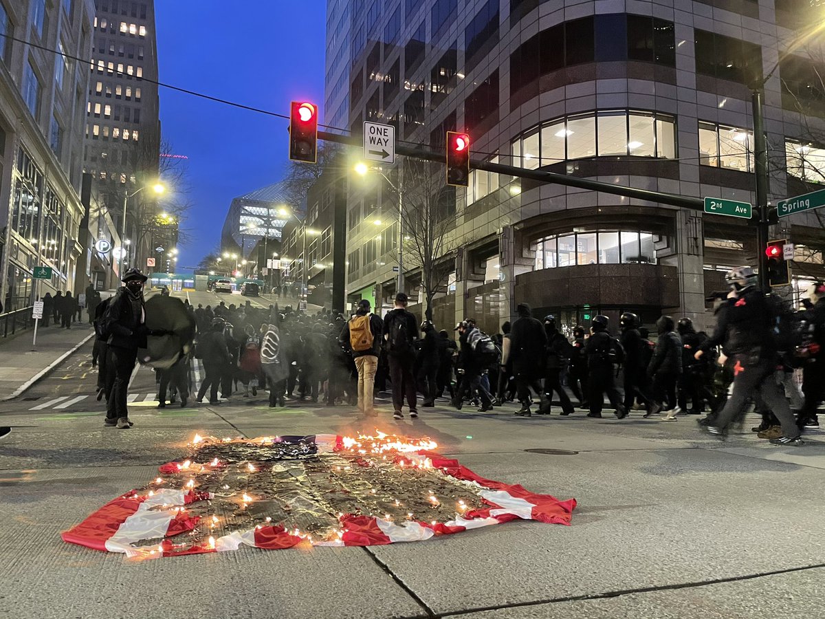 In Seattle, a group of about 150 protesters in black bloc burned an American flag outside the immigration court on 2nd Ave, smashed a window at the Amazon Go. Police are now trailing.